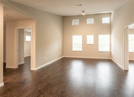A large empty room with wooden floors and windows.