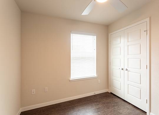 A room with a white door and a window with blinds.