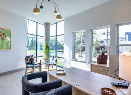 A room with a desk, chairs, and a painting on the wall.