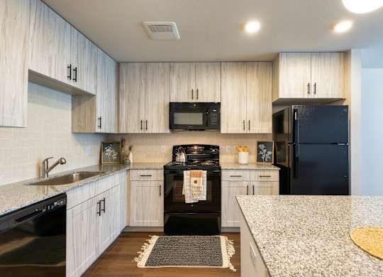 A kitchen with black appliances and white cabinets.