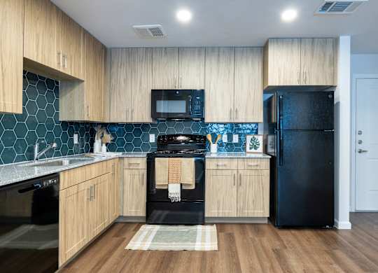 A kitchen with wooden cabinets and black appliances.