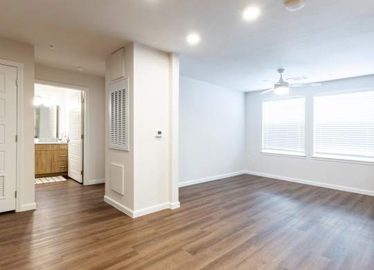 A room with wooden floors and a window with blinds.