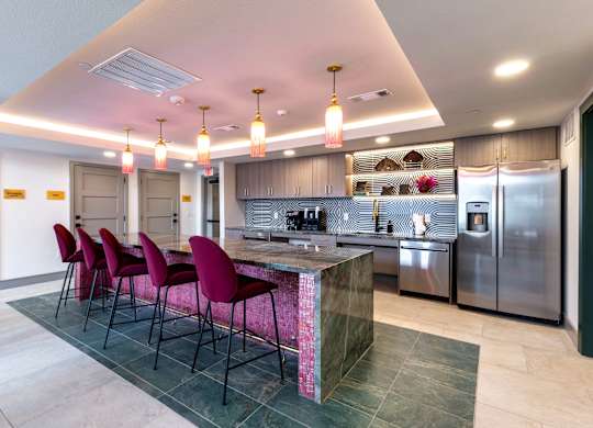 A kitchen with a marble island and red chairs.
