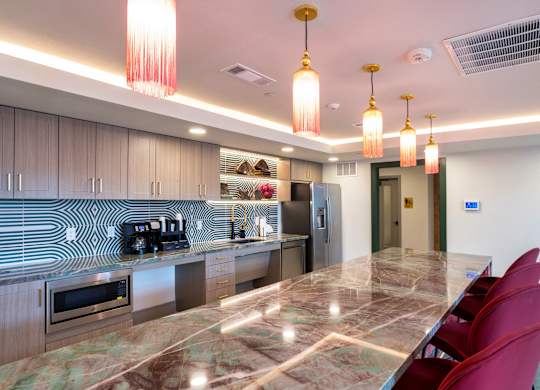 A kitchen with a marble countertop and red chairs.