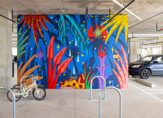 A motorcycle is parked in front of a colorful mural.