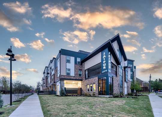 A modern apartment building with a well-maintained lawn in front.