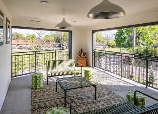 A balcony with a table and chairs overlooking a street.