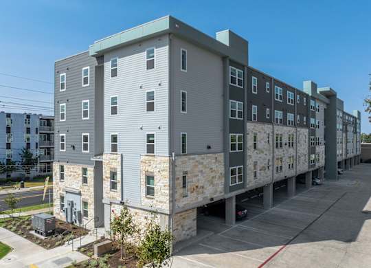 A large apartment complex with a parking lot in front.