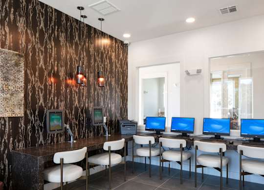 A room with a brown marble wall and a row of computers on desks.