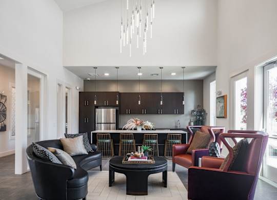 A modern living room with a black leather couch and a chandelier.
