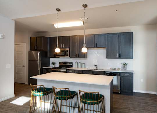 A kitchen with a white island and black cabinets.