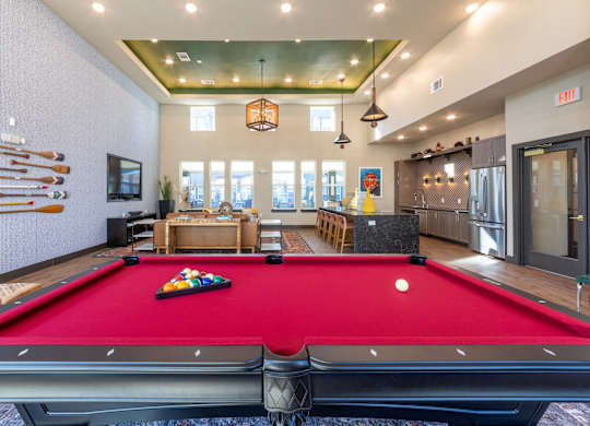 A pool table is in the middle of a room with a red carpet.