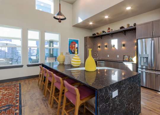 A kitchen with a black counter top and wooden chairs.