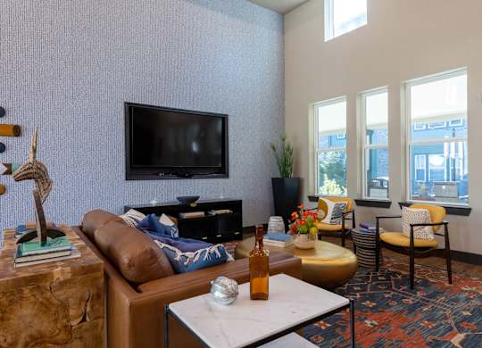 A living room with a brown couch, a white coffee table, and a flat screen TV mounted on the wall.