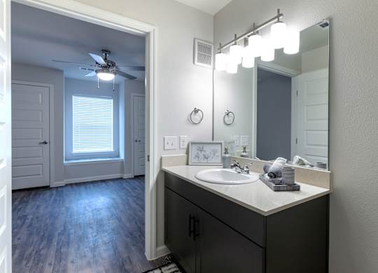 A bathroom with a sink, mirror, and lighting fixtures.