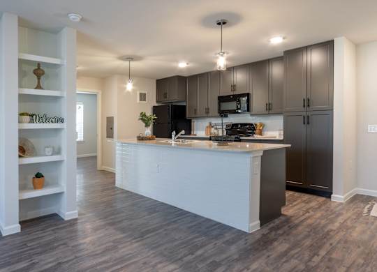 A modern kitchen with a white island and dark wood cabinets.