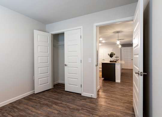 A room with white walls and a wooden floor with three white doors.