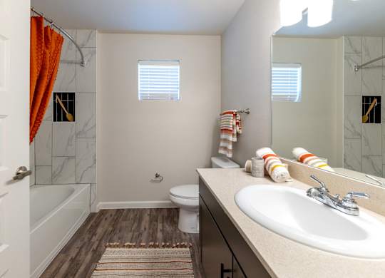 A bathroom with a white sink, toilet, and a shower with a red shower curtain.