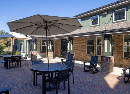 A patio with a table and chairs under an umbrella.