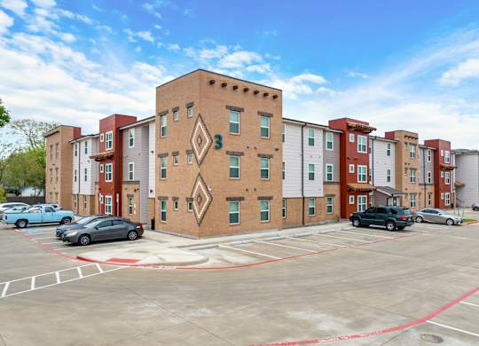 A parking lot in front of a multi-story apartment building.