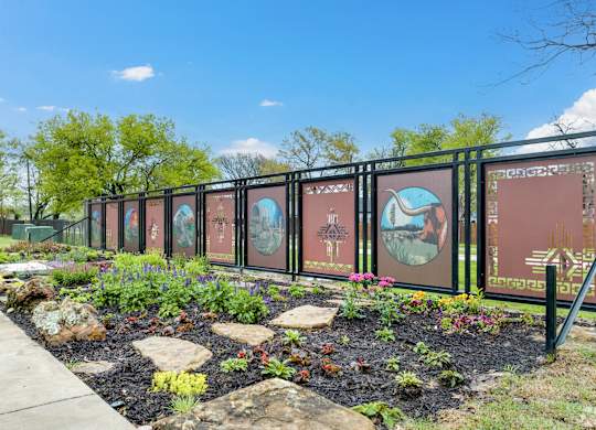 A garden with a fence and a signboard with pictures and text.