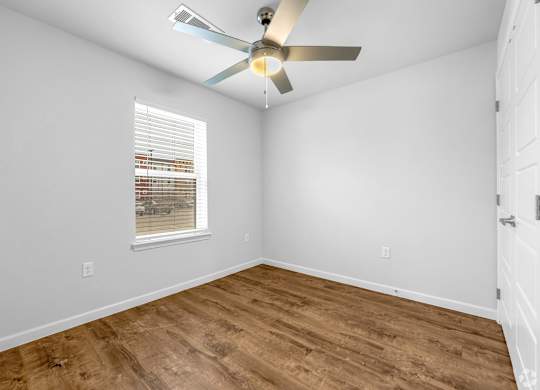 A room with a ceiling fan and a window with blinds.