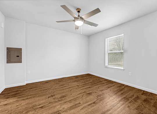 A room with a ceiling fan and wooden flooring.