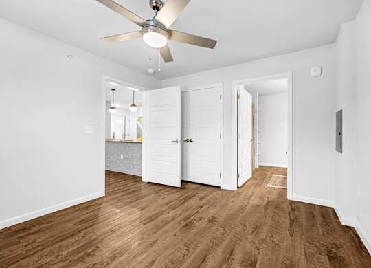 A room with a ceiling fan and wooden flooring.