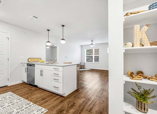 A kitchen with white cabinets and a wooden floor.