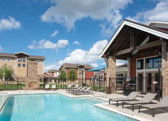 A swimming pool with lounge chairs and a building in the background.
