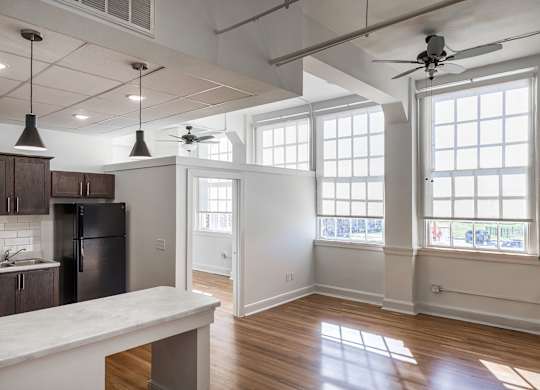 A kitchen with a refrigerator, cabinets, and a marble countertop.