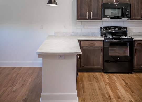 A kitchen with a white island and dark brown cabinets.