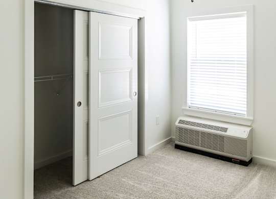 A room with a ceiling fan and a window with blinds.