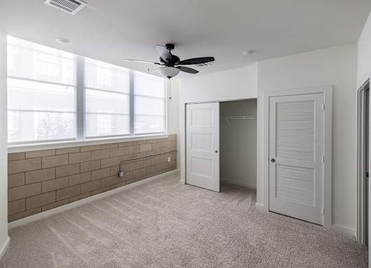 A room with a ceiling fan and a window.