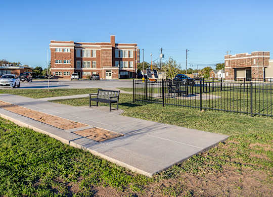 A park with a bench and a pathway leading to a building.