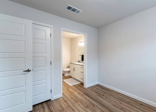 A white bathroom with a toilet, sink, and wooden floors.