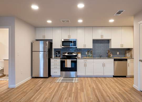 A kitchen with wooden floors and white cabinets.