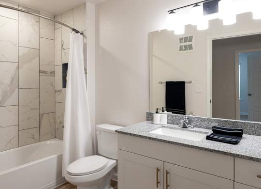 A white bathroom with a marble tile shower.