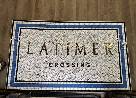 A mosaic sign that says "Latimer Crossing" is displayed on a wooden surface.