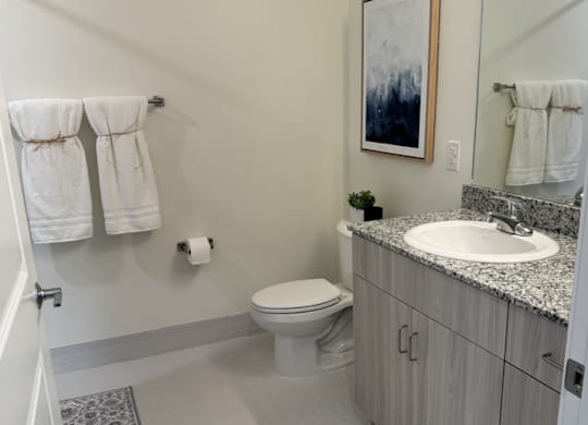 A bathroom with a toilet, sink, and towels.