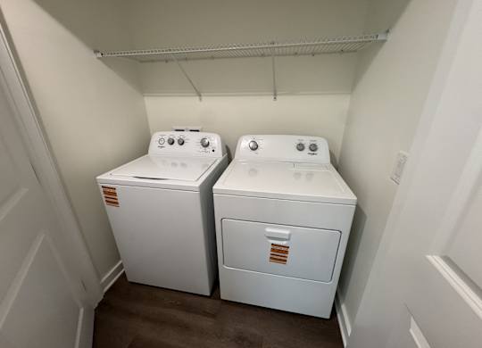 Two white front loading washing machines in a small laundry room.