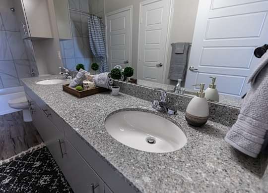 A bathroom with a white sink and a grey counter top.