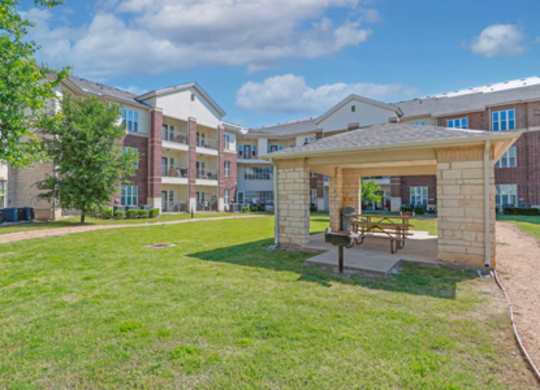 A grassy area in front of apartment buildings with a picnic table.