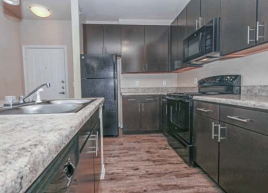 A kitchen with a granite countertop and stainless steel appliances.