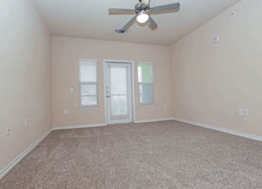 A room with a ceiling fan and carpeted floor.