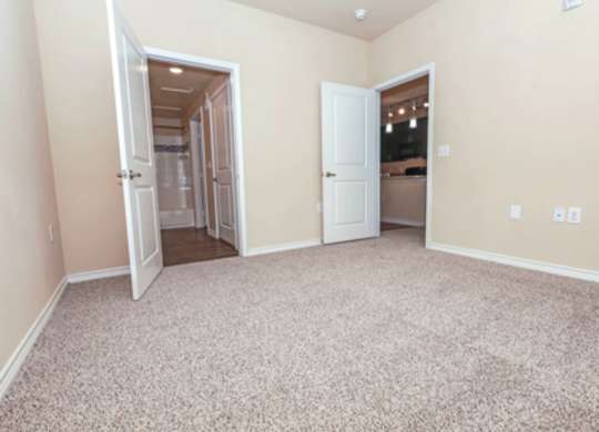 A room with a carpeted floor and two open doors.