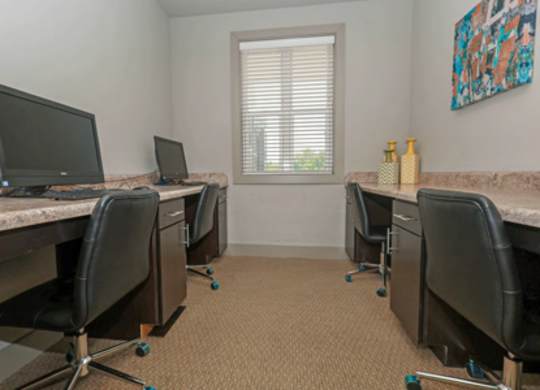 A room with a desk and chairs and a window.