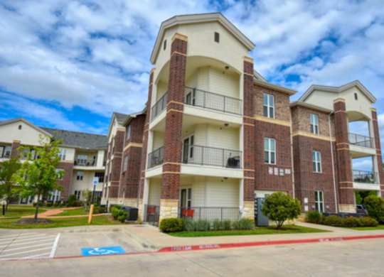 A large apartment building with a parking lot in front.