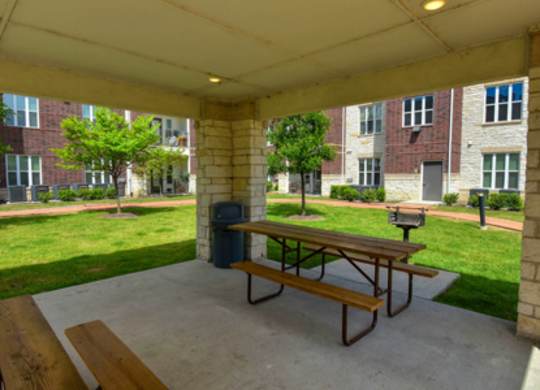 A covered patio with a picnic table and benches.