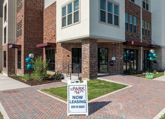 A brick building with a sign that says "Park 142 No Leasing Stop In Today".